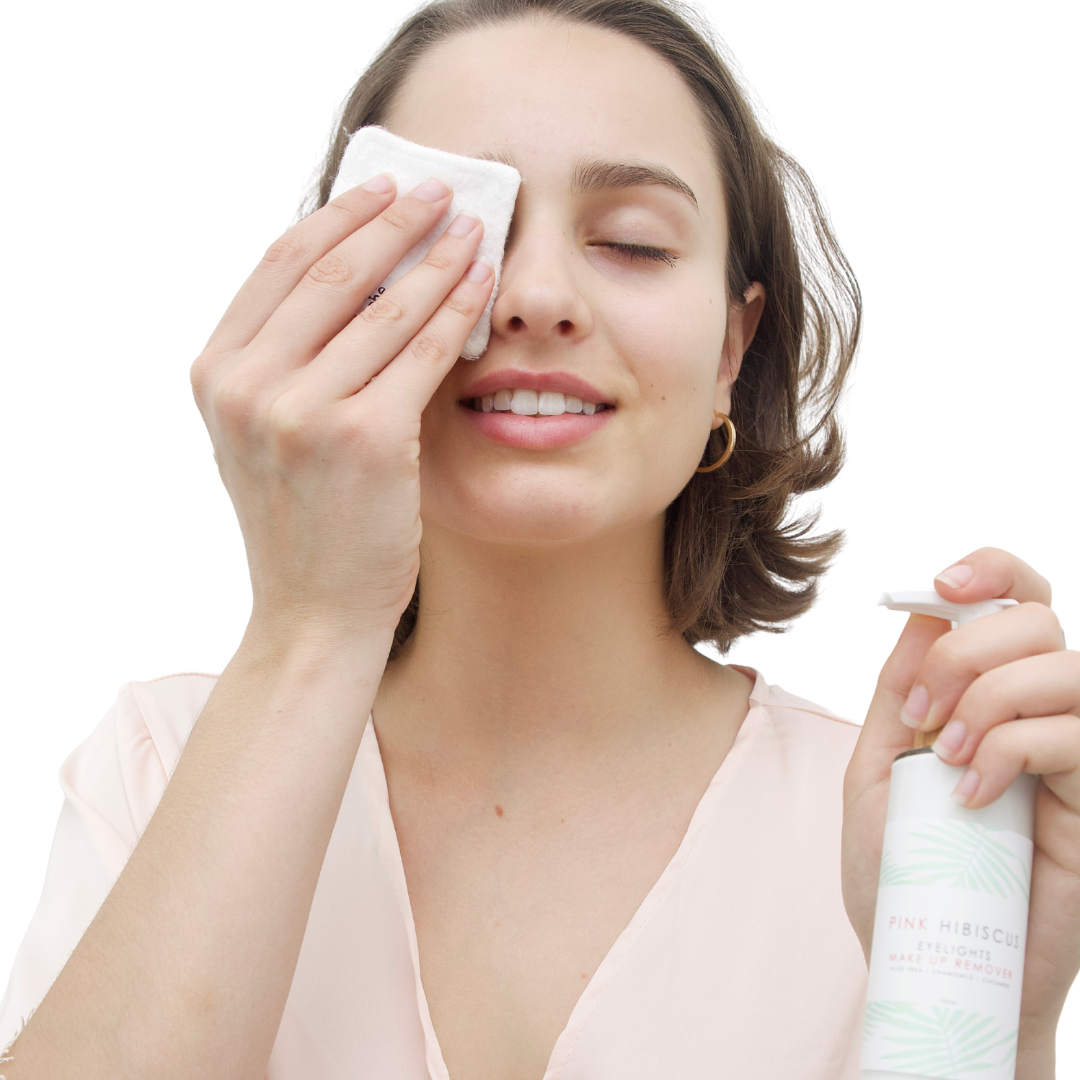 Caucasian woman removing eye make up using Pink Hibiscus Eyelights Make Up Remover and Pink Hibiscus Bamboo Cosmetic Pad